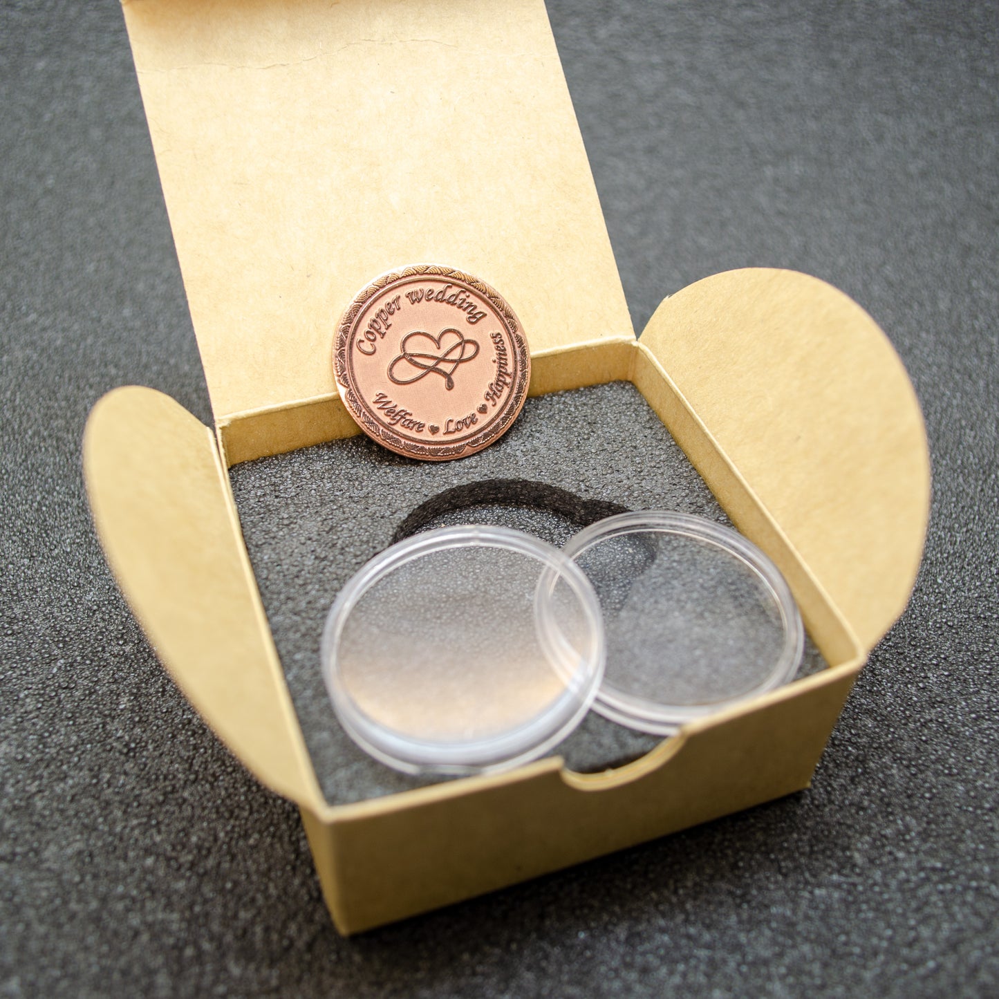 Engraved copper love coin for 7 years of marriage celebration, personalized gift inside a craft paper box with foam insert.