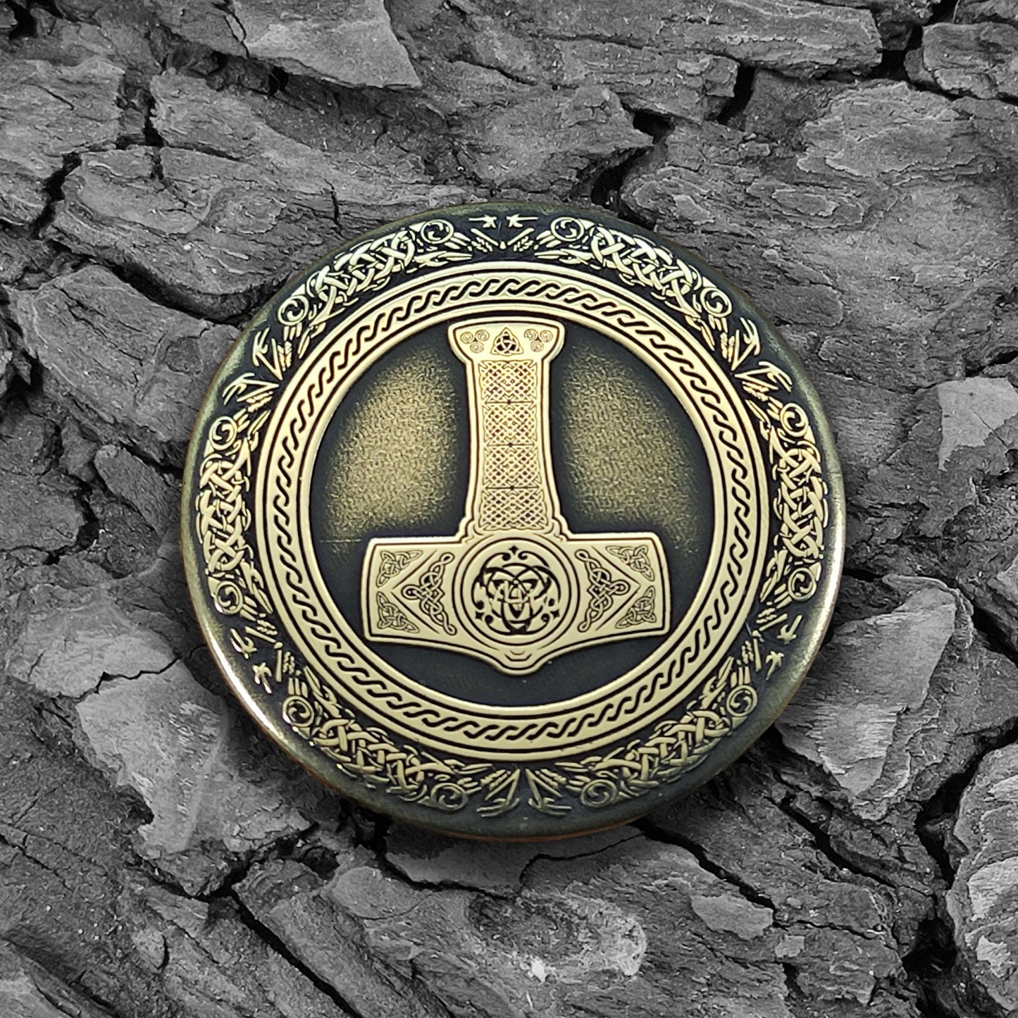 Viking brass amulet Thor's Hammer Mjolnir on a natural dark wood texture background.