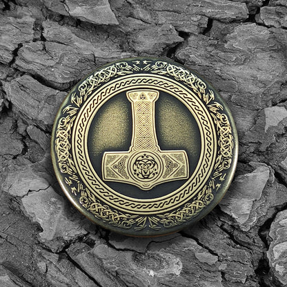 Viking brass amulet Thor's Hammer Mjolnir on a natural dark wood texture background.