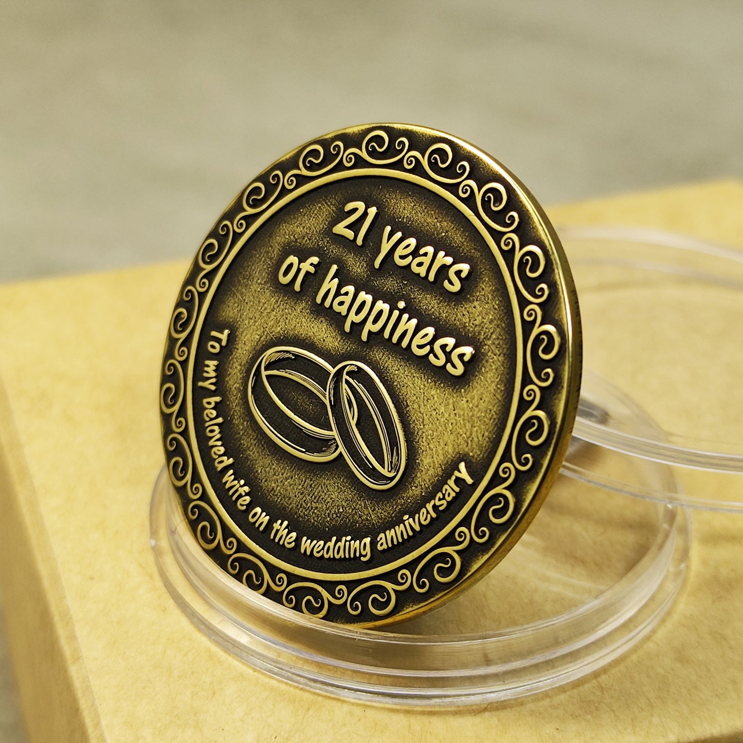 Close-up of the hand-polished brass coin for 21st anniversary, showing deep relief engraving, aged metal texture, and vintage patina.