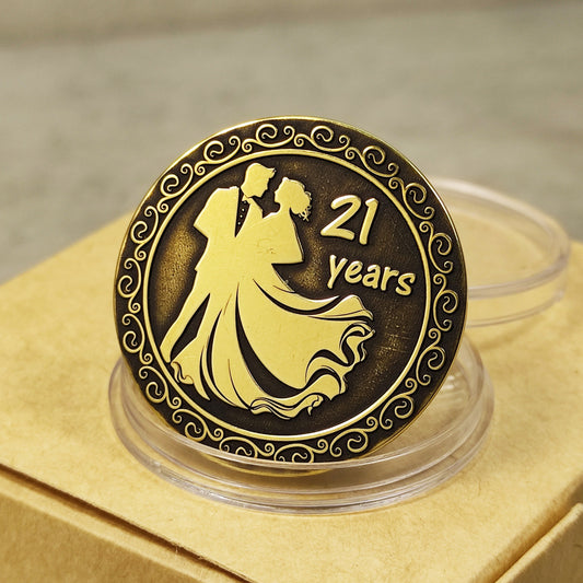 Close-up of 21 years brass wedding anniversary coin with couple silhouette engraving and vintage patina finish.