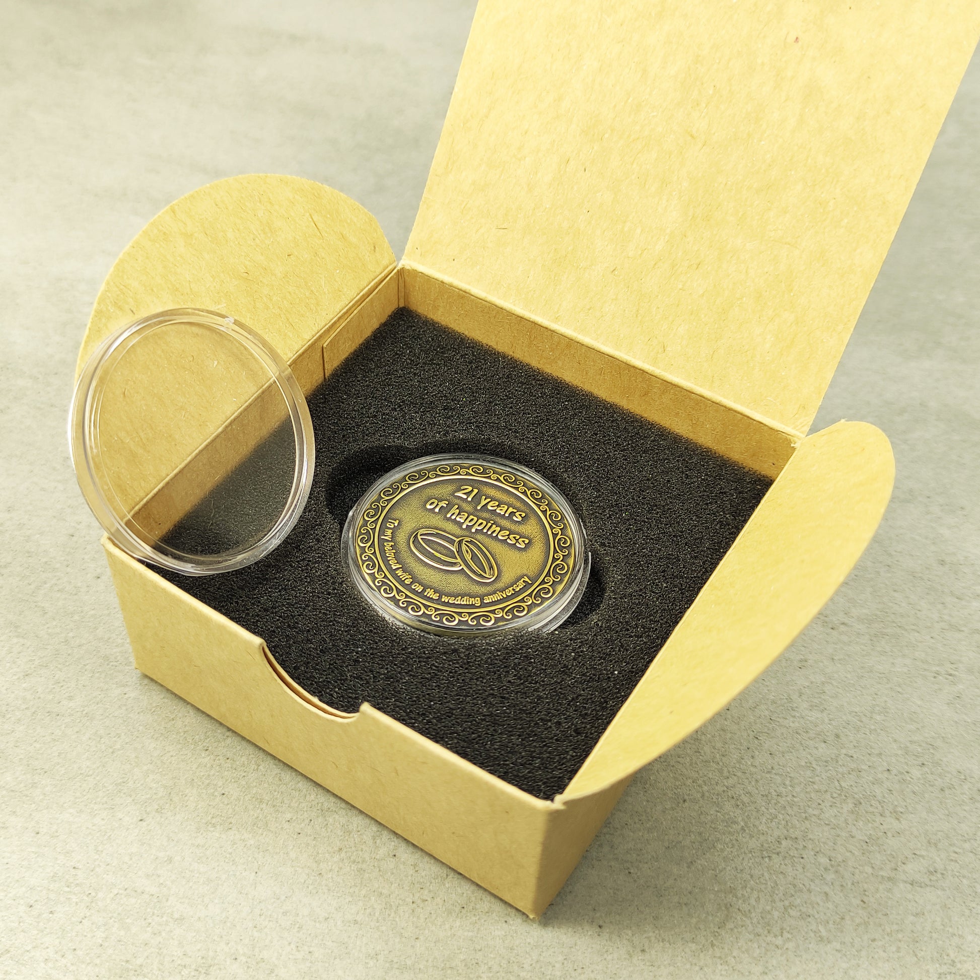 Personalized brass metal coin in a clear protective acrylic case next to a minimalist eco-friendly gift box for a brass wedding anniversary.