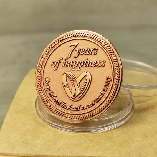 7th wedding anniversary copper coin with deep engraving of rings and "7 years of happiness", polished mirror finish, obverse view.