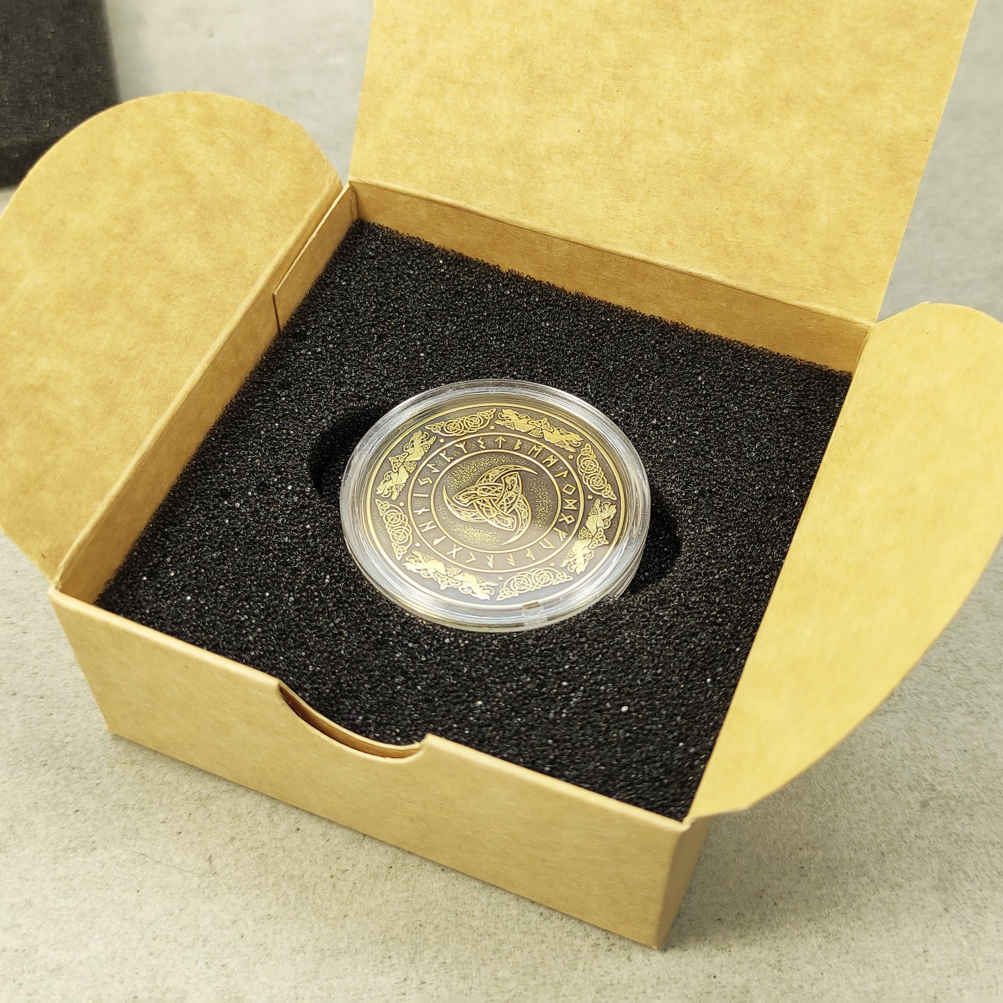 Personalized brass souvenir coin in a protective acrylic capsule and craft gift box, premium presentation of a Norse mythology gift.