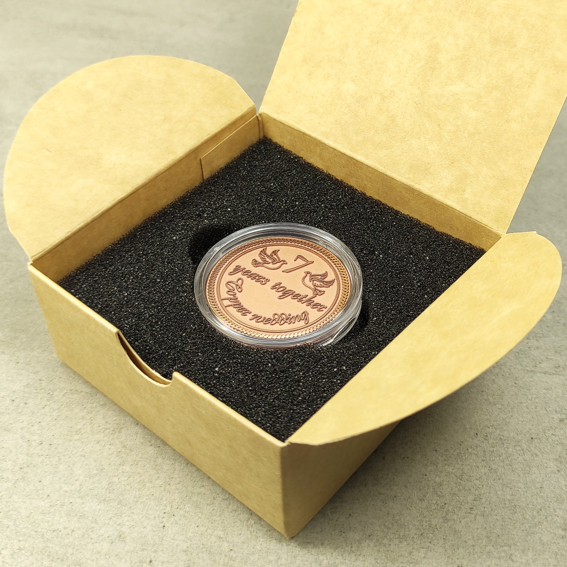 Top view of a personalized copper anniversary coin in a gift box, custom wedding date engraving, elegant commemorative gift in capsule.