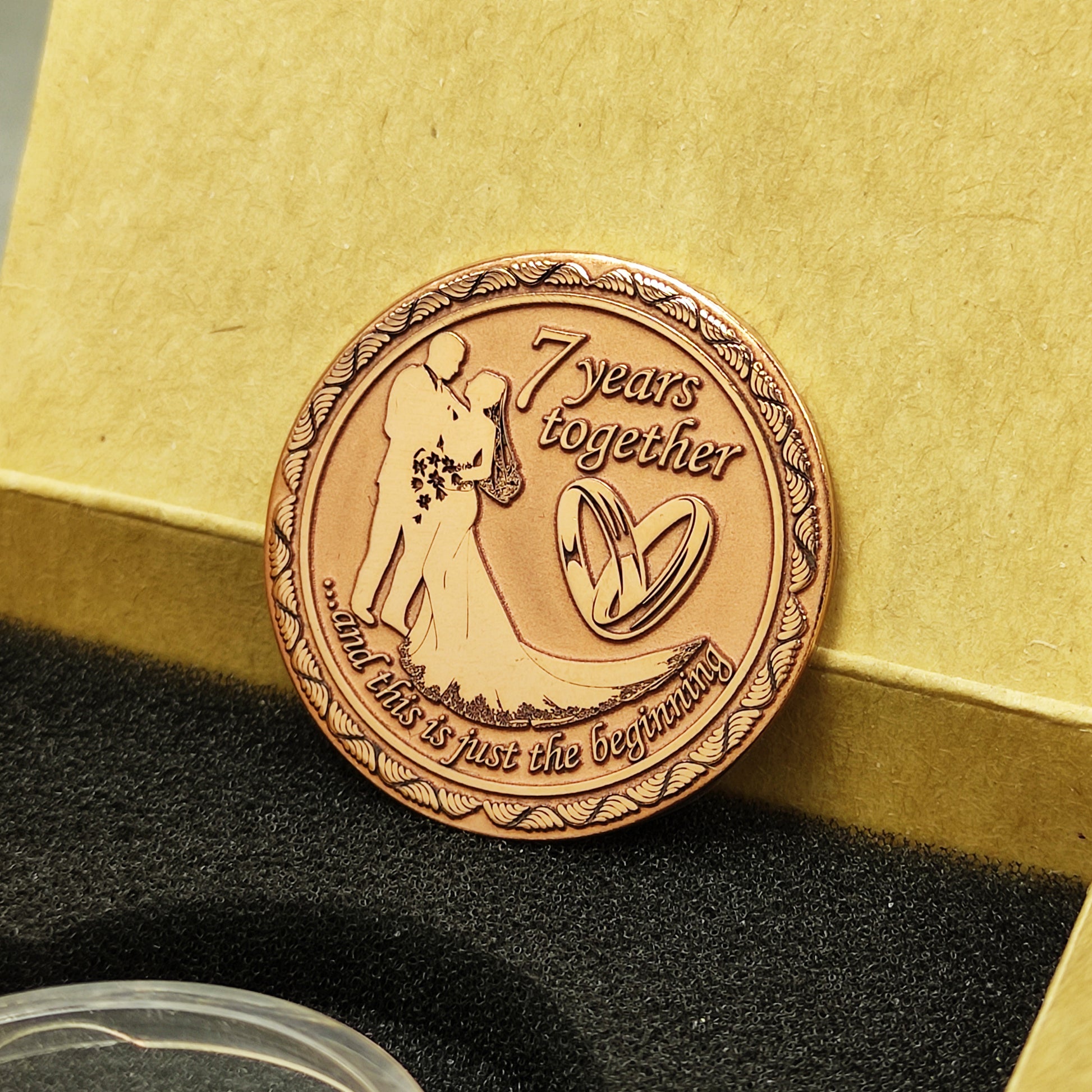 Engraved copper love coin for 7 years of marriage celebration, personalized anniversary gift inside a craft paper box with foam insert.