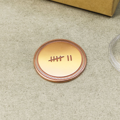Minimalist 7 year anniversary copper token, hand-polished metal coin with decorative border and engraved tally symbols.