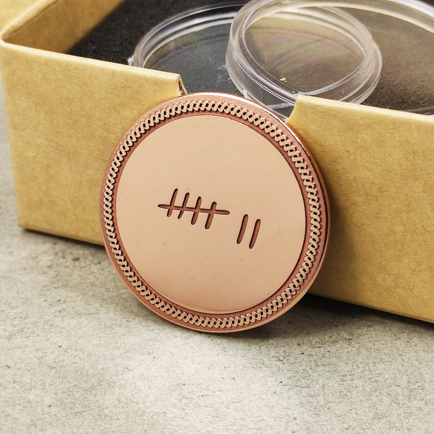 Personalized copper anniversary gift for husband, "7 years" tally mark coin leaning on a craft paper gift box.