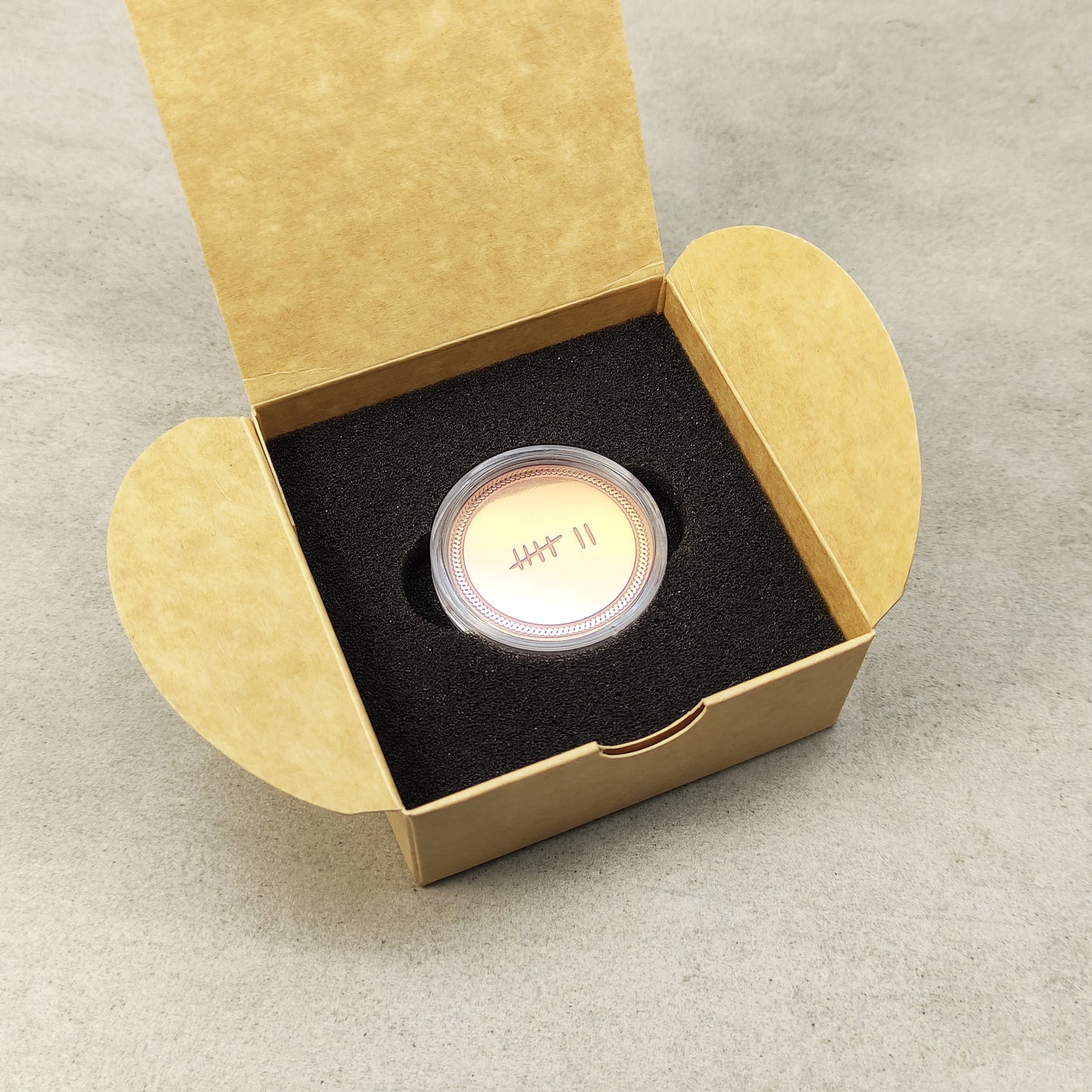 Top view of a personalized copper anniversary coin in gift box, custom tally marks engraving, elegant commemorative gift.