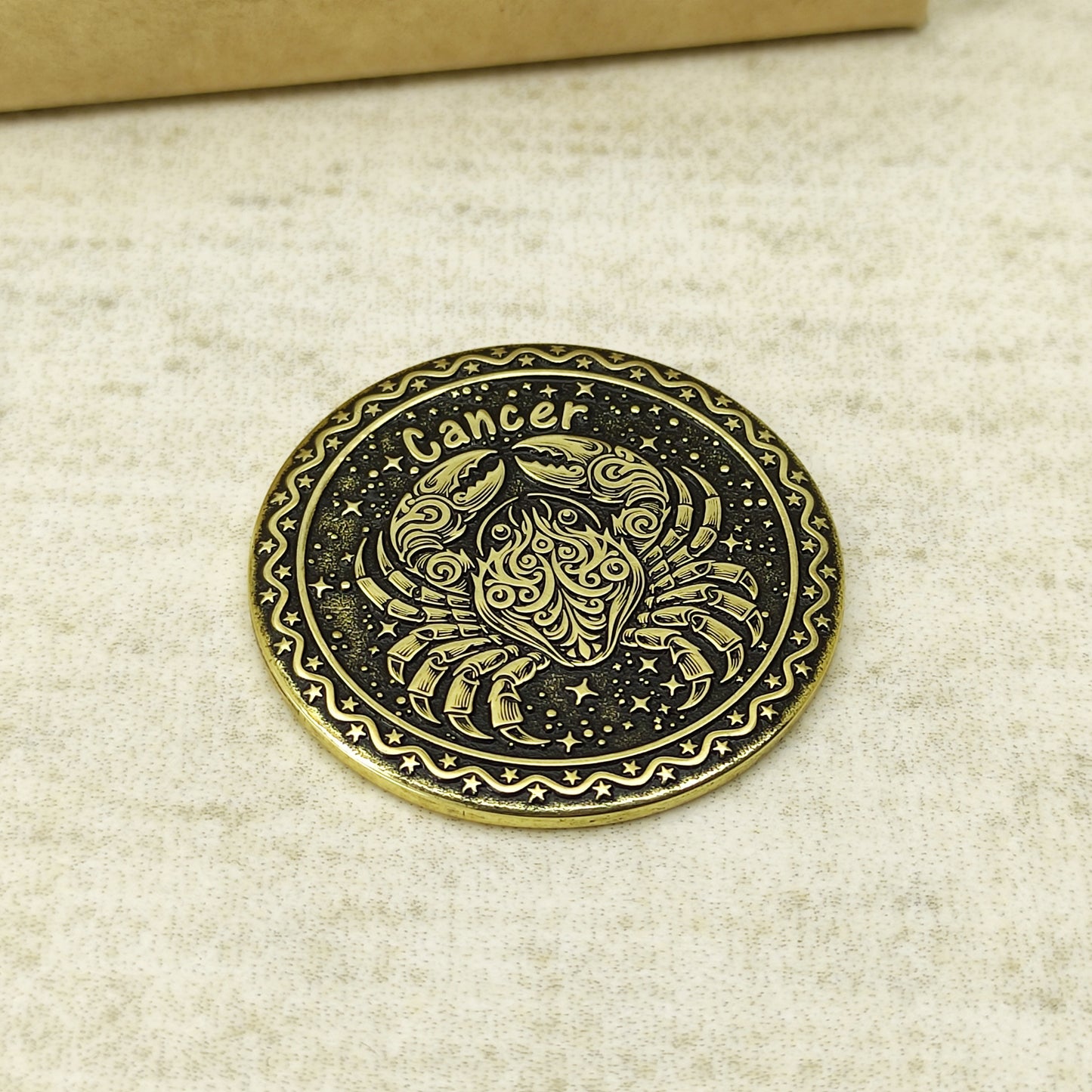 Detailed view of the Cancer zodiac brass medal, highlighting the intricate 3D-style engraving and dark recessed patina on the polished brass surface.