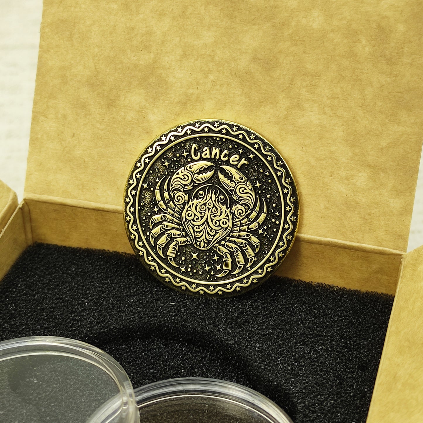 Custom Cancer zodiac brass coin in a premium gift box with black foam insert, highlighting the gold-tone brass material and dark engraved details.