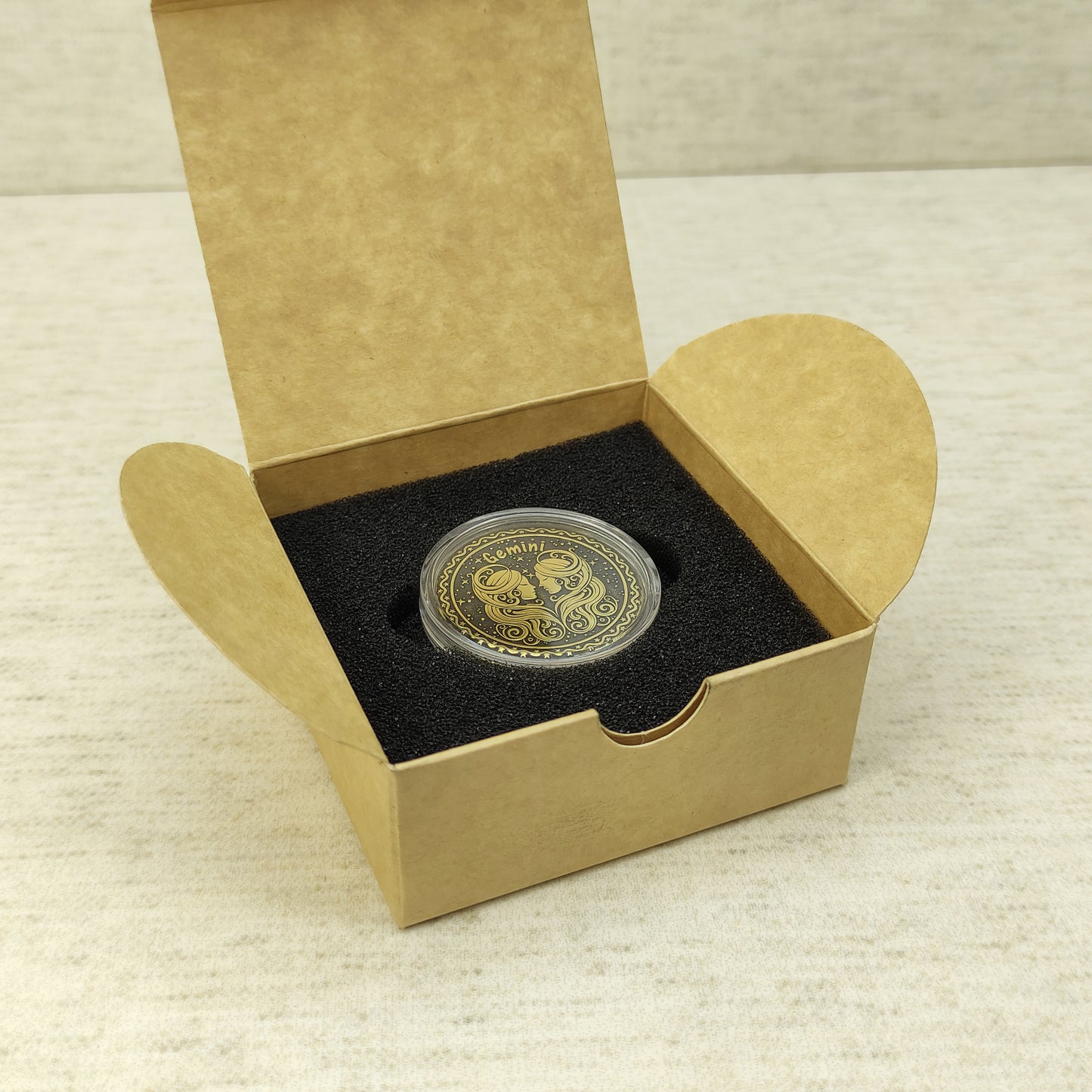 Gemini zodiac brass medal in a small square craft gift box, professional presentation of a personalized astrology souvenir with dark patina finish.
