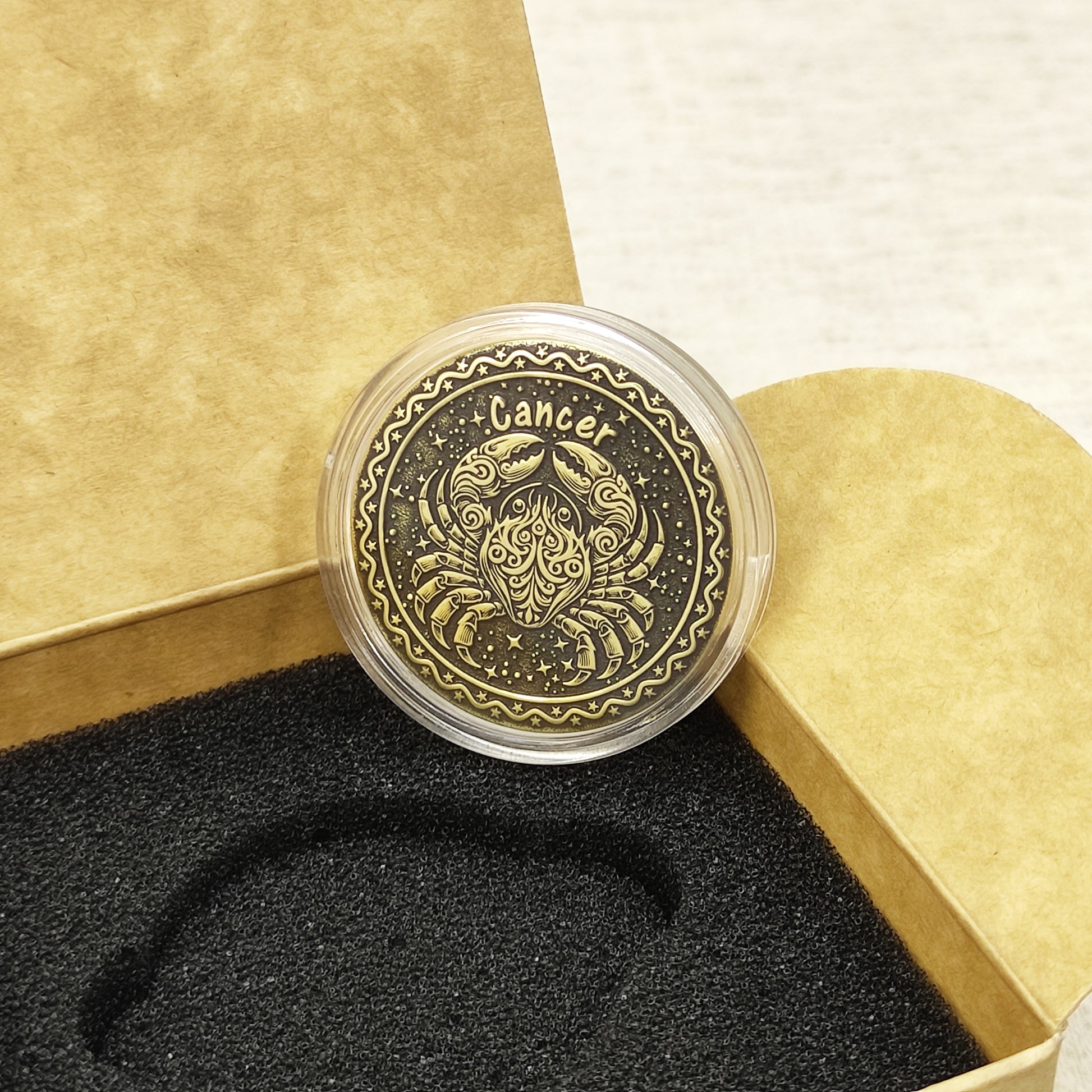 Top view of the Cancer zodiac medal in a protective acrylic capsule, handcrafted brass coin gift for astrology lovers with personalized laser etching.