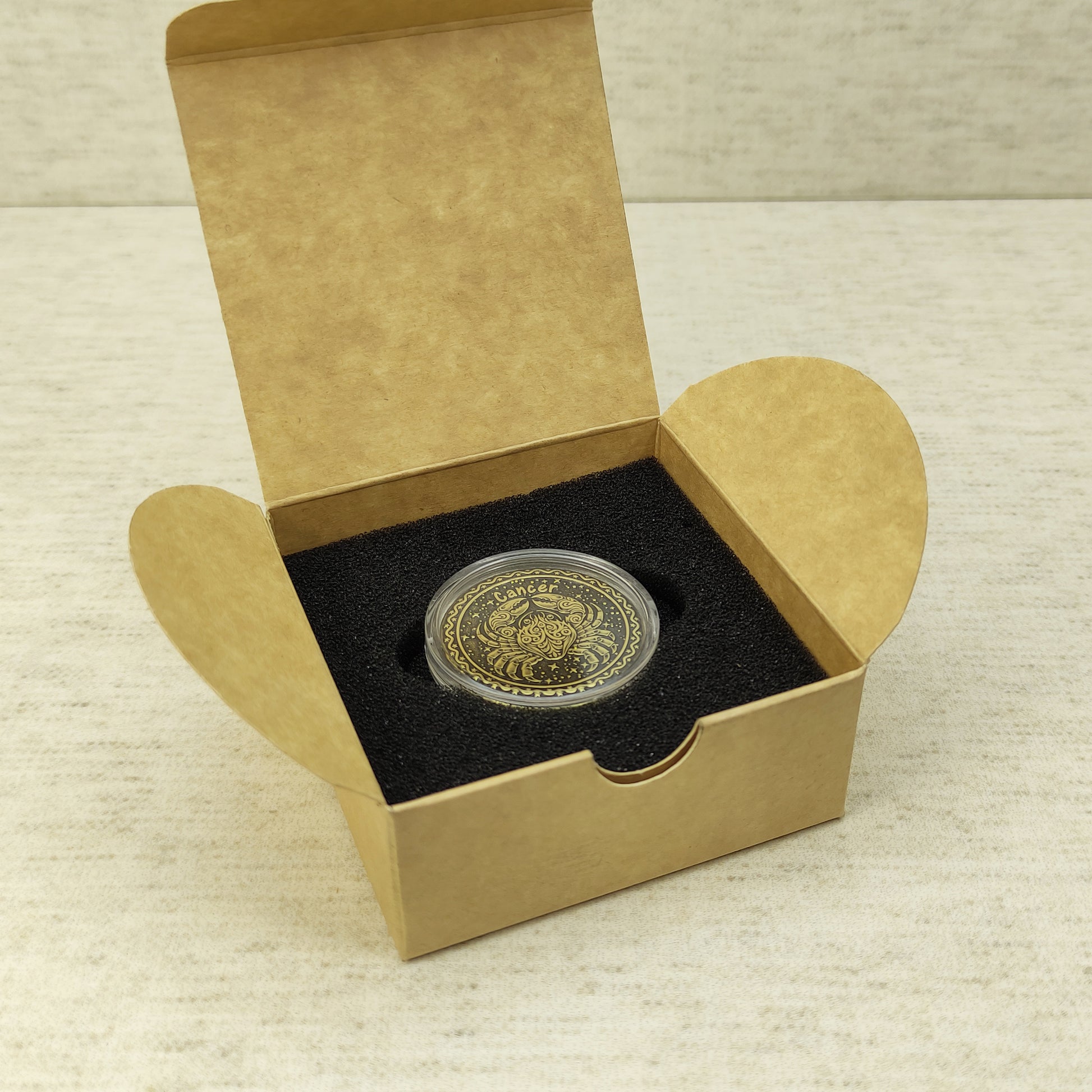 Cancer zodiac brass medal in a small square craft gift box, professional presentation of a personalized astrology souvenir with dark patina finish.