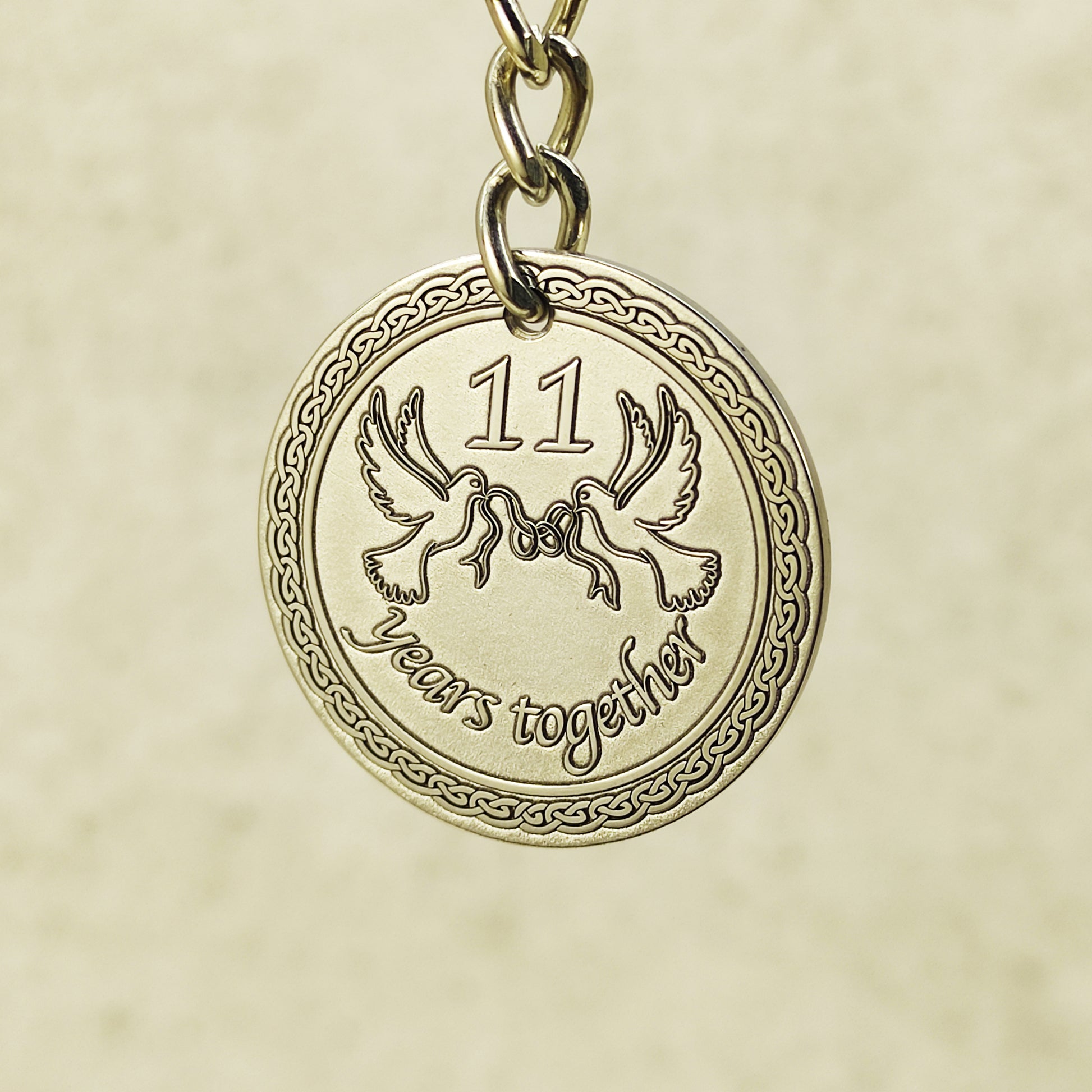 Close-up of handcrafted stainless steel coin pendant for 11th anniversary featuring "11 years together" text.