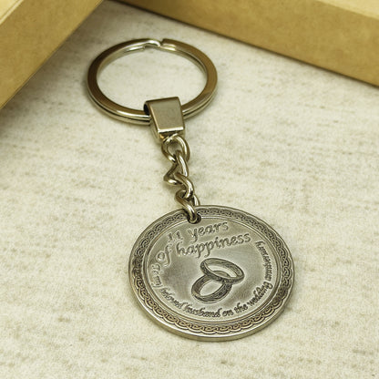 Custom engraved brass coin keychain for 11th steel wedding anniversary, featuring a polished metal finish with dark recessed engraving for high contrast.