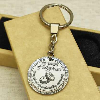 Custom engraved brass coin keychain for 11th steel wedding anniversary, highlighting the contrast between polished metal and dark recessed engraving.