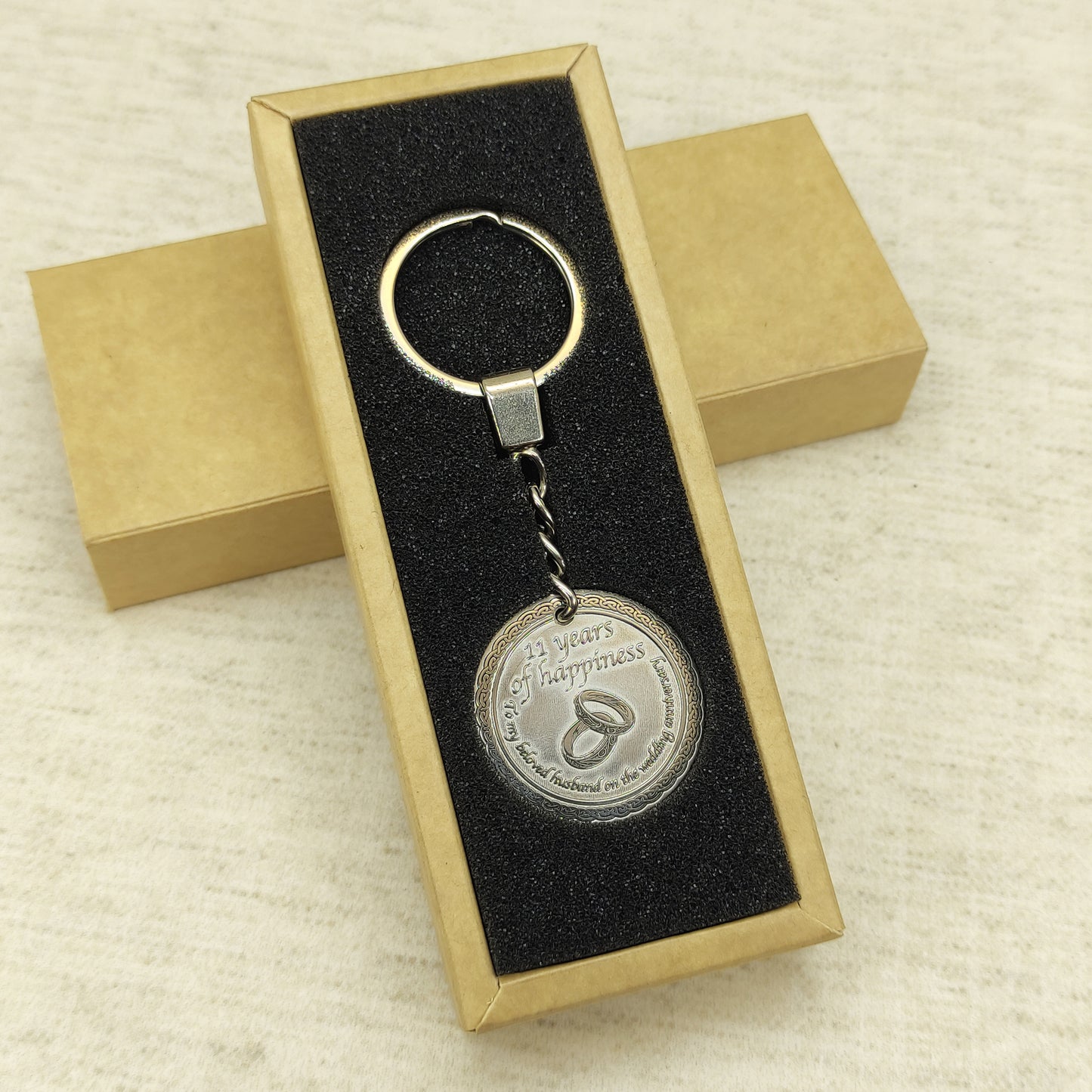 Brass anniversary keychain presented in a minimalist gift box with black insert, high-quality personalized metal gift for 11 years of marriage celebration.
