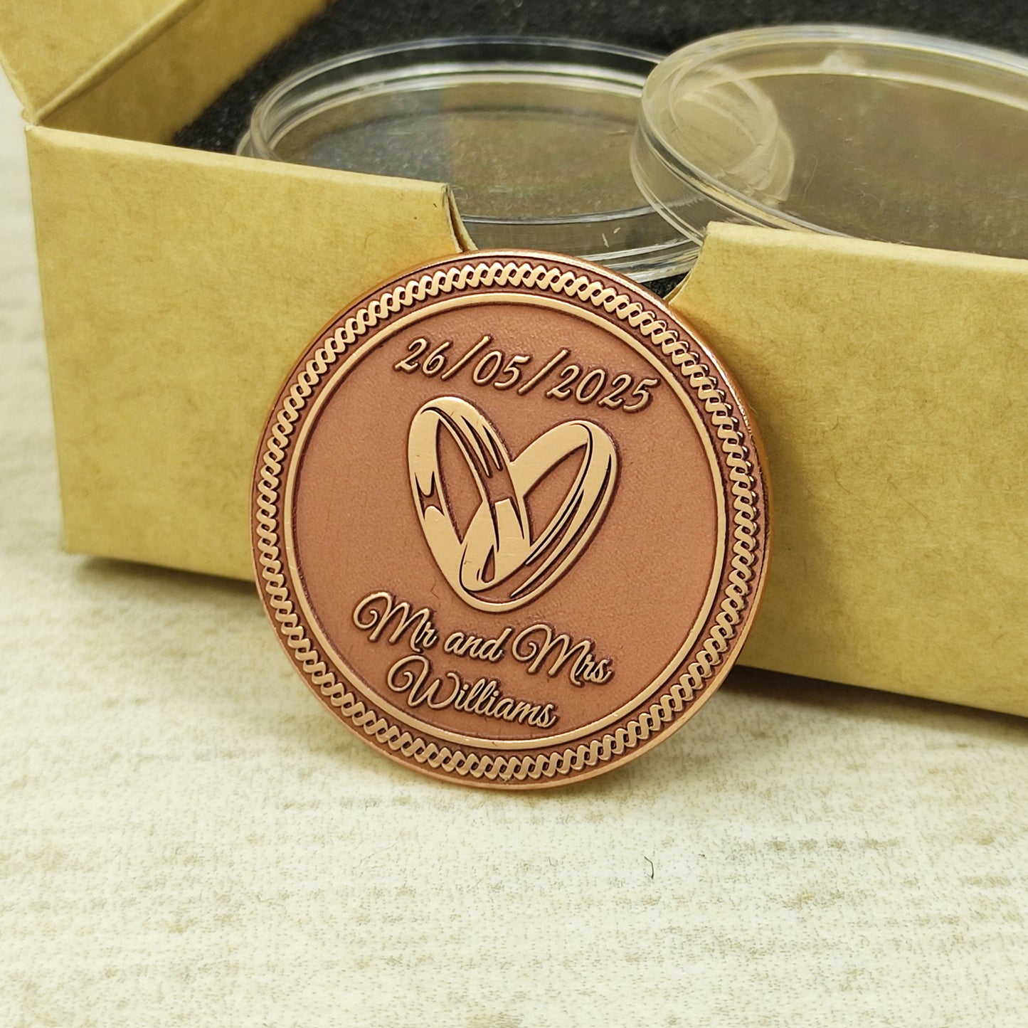 Personalized copper commemorative medal for weddings, leaning against a gift box to show the warm copper tone and precision etching.