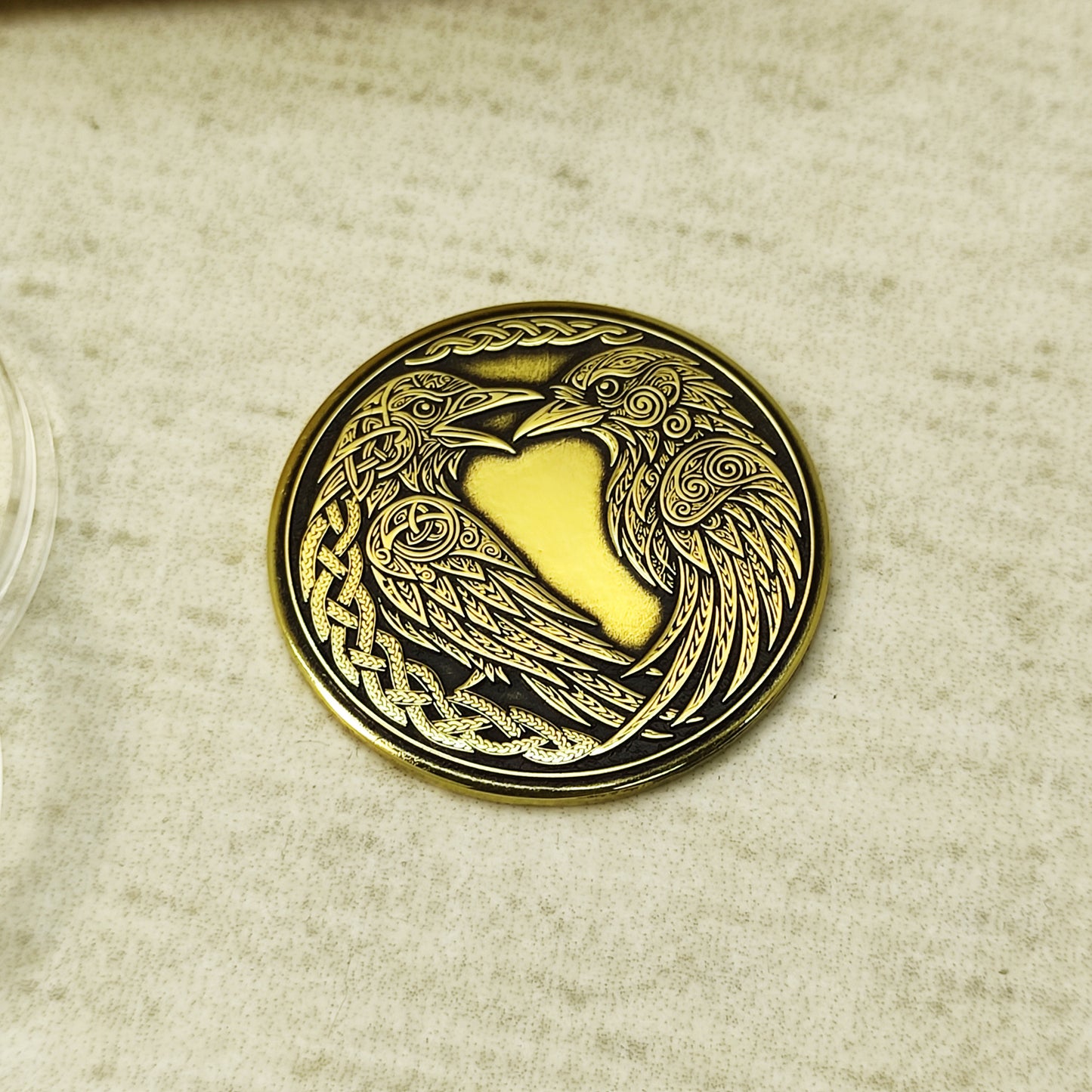 Customized Norse ravens brass coin on a flat surface, 32mm diameter handcrafted souvenir with Celtic knotwork borders.