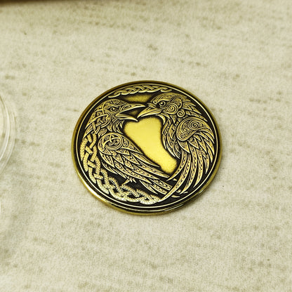 Customized Norse ravens brass coin on a flat surface, 32mm diameter handcrafted souvenir with Celtic knotwork borders.