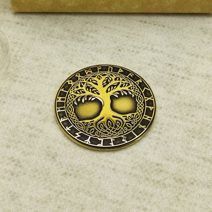 Top view of a brass Yggdrasil amulet coin featuring intricate laser engraving of the Norse World Tree and Elder Futhark runes.