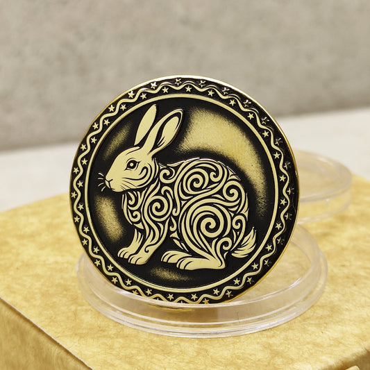 Close-up of a brass Chinese zodiac coin Year of the Rabbit, featuring deep laser engraving, antique patina finish, and decorative star border on a gift box.