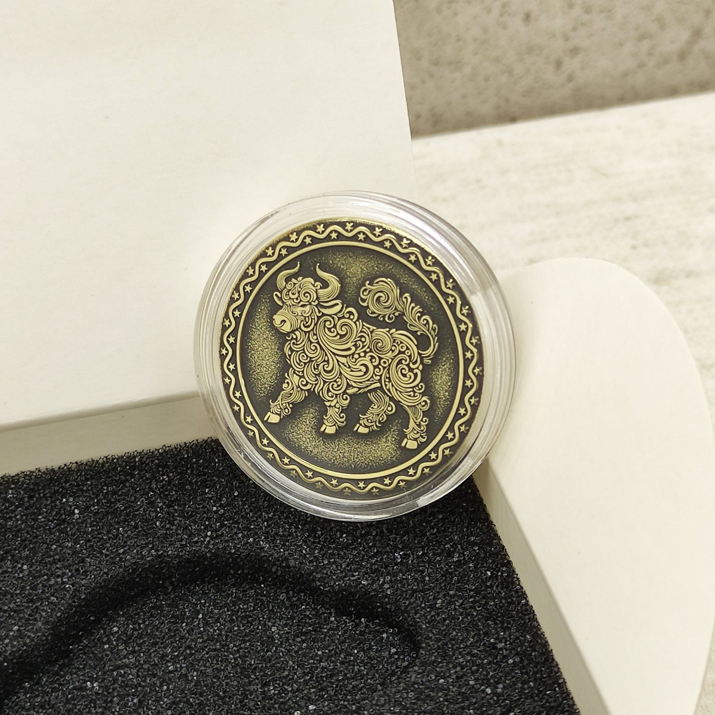 Macro photo of the brass Ox coin in a protective capsule, highlighting the intricate dark recessed patina engraving for high contrast.