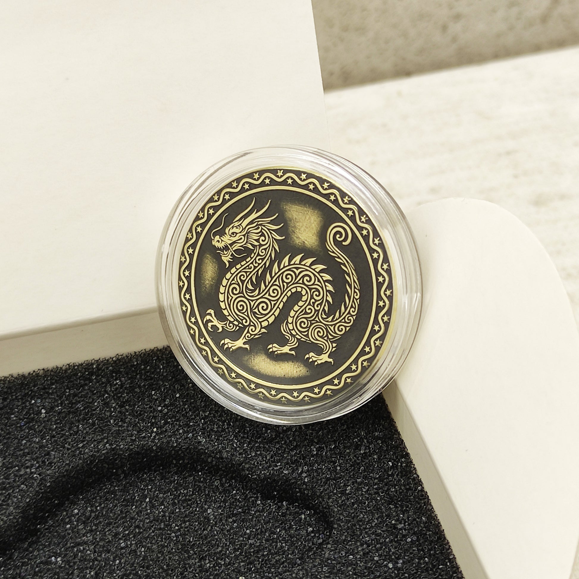 Macro photo of the brass Dragon coin in a protective capsule, highlighting the intricate dark recessed patina engraving for high contrast.