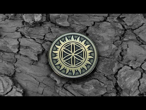 Handcrafted Slavic protective talisman brass coin with Perun Star symbol placed on a dark wooden background.
