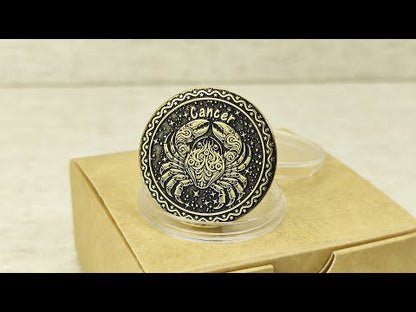 Personalized brass Cancer zodiac coin placed on a craft gift box, showcasing the durable metal texture and high-contrast professional patina treatment.