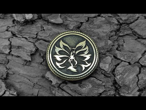 Nine-tailed fox Kitsune brass coin placed on dark wood bark background, showcasing golden metal contrast and fine engraving.